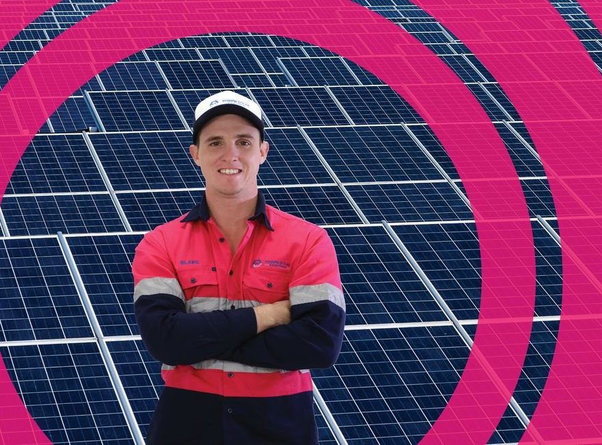 Blake Popp in Popp'N Solar workwear, standing in front of solar panels